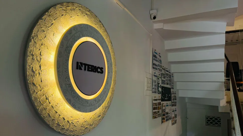 Illuminated Interics wall logo with textured circular installation showcasing creative office branding design