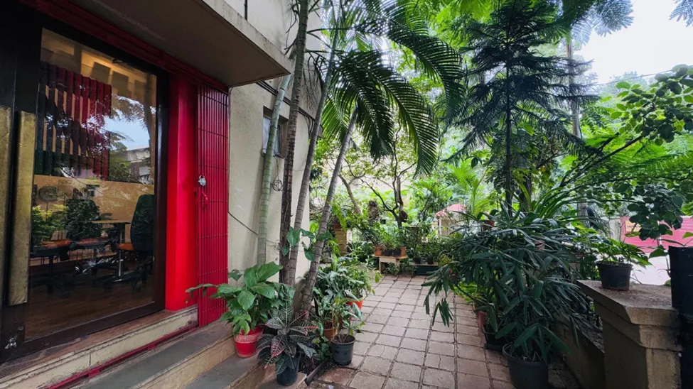 Office entrance with lush green landscape and outdoor walkway showcasing nature-inspired workspace design